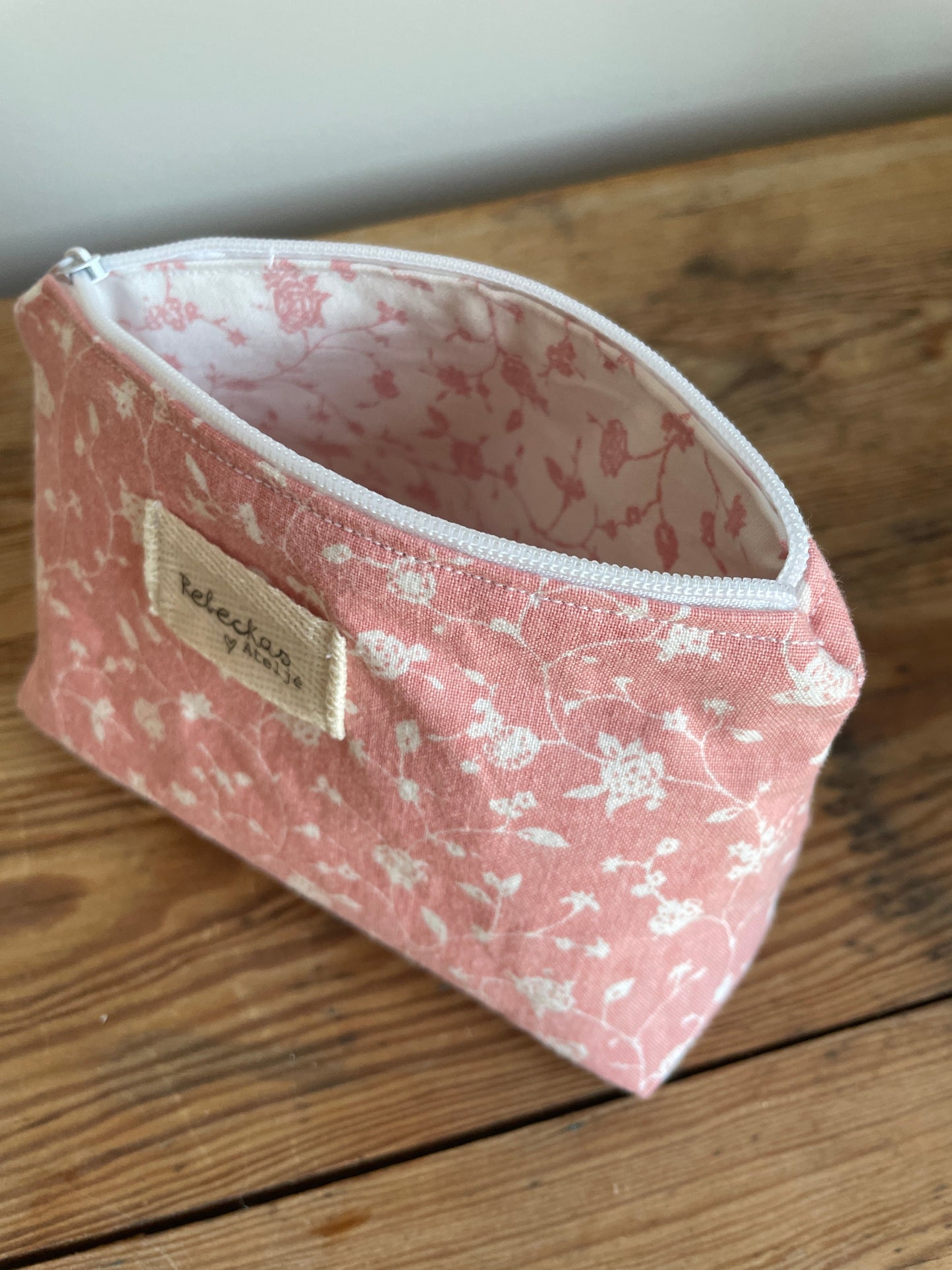 Klassisk necessär i tyg med rosa mönster och vita blommor, med dragkedja upptill