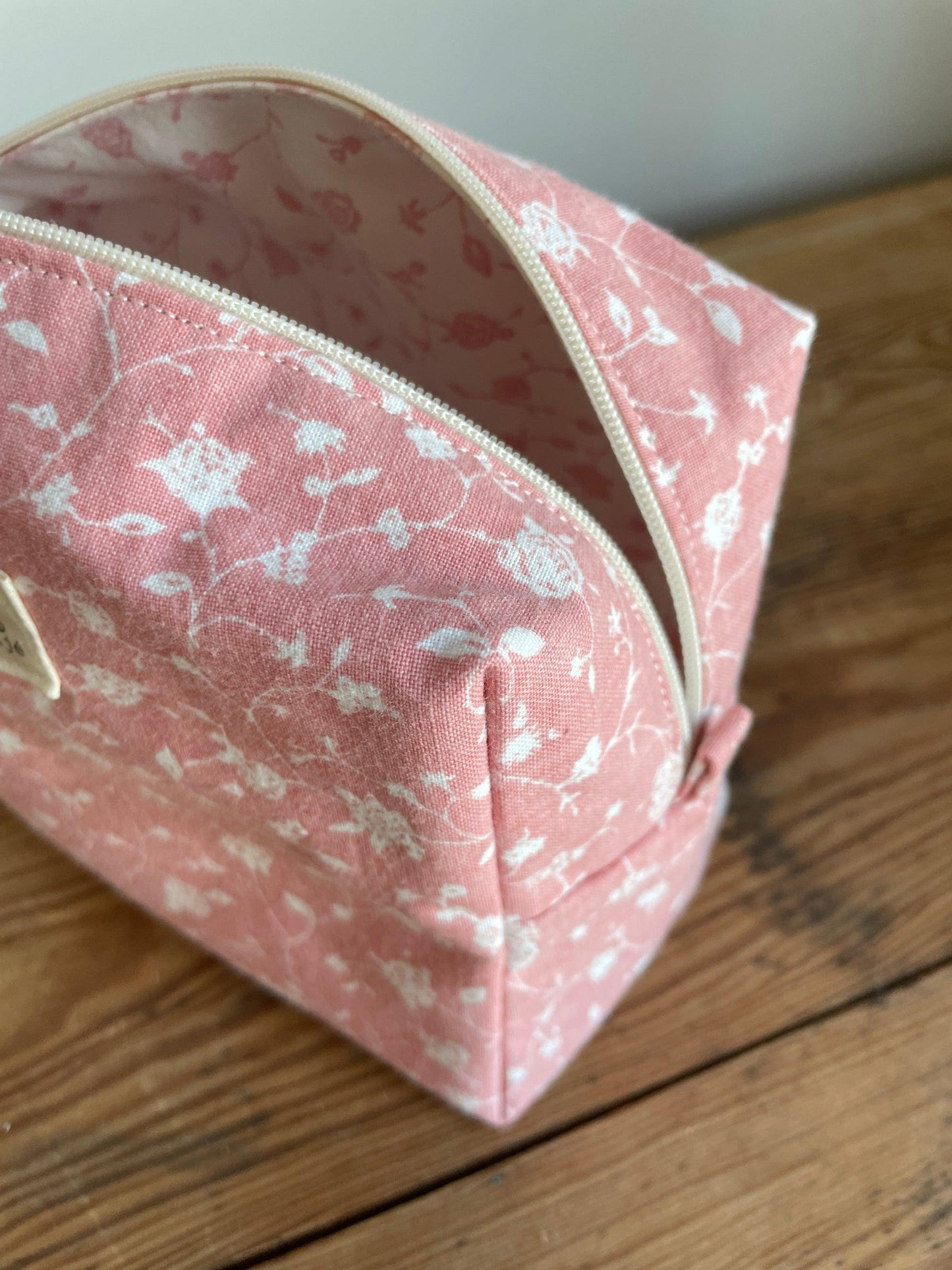 Handgjord boxnecessär i tyg med rosa bakgrund, små vita blommor och dragkedja