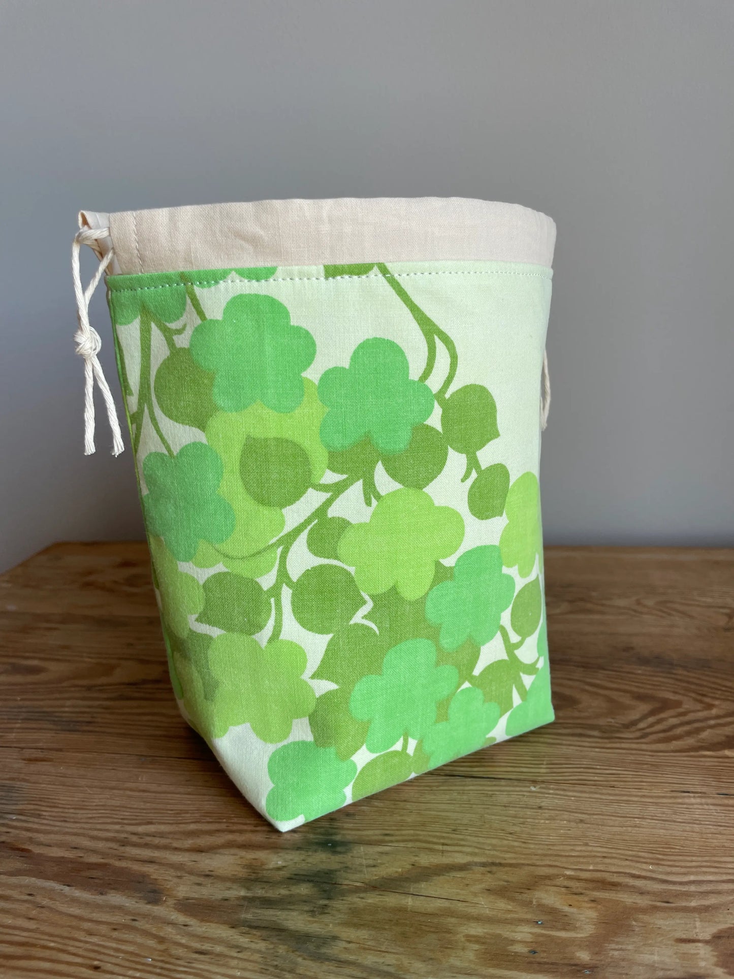 Handsydd liten projektpåse med dragsko i grönt bomullstyg med retroinspirerat blommönster. Praktisk förvaring för sockstickning, garn, virkning och andra mindre handarbetsprojekt. Rymlig projektväska i kompakt format för stickare och virkare.