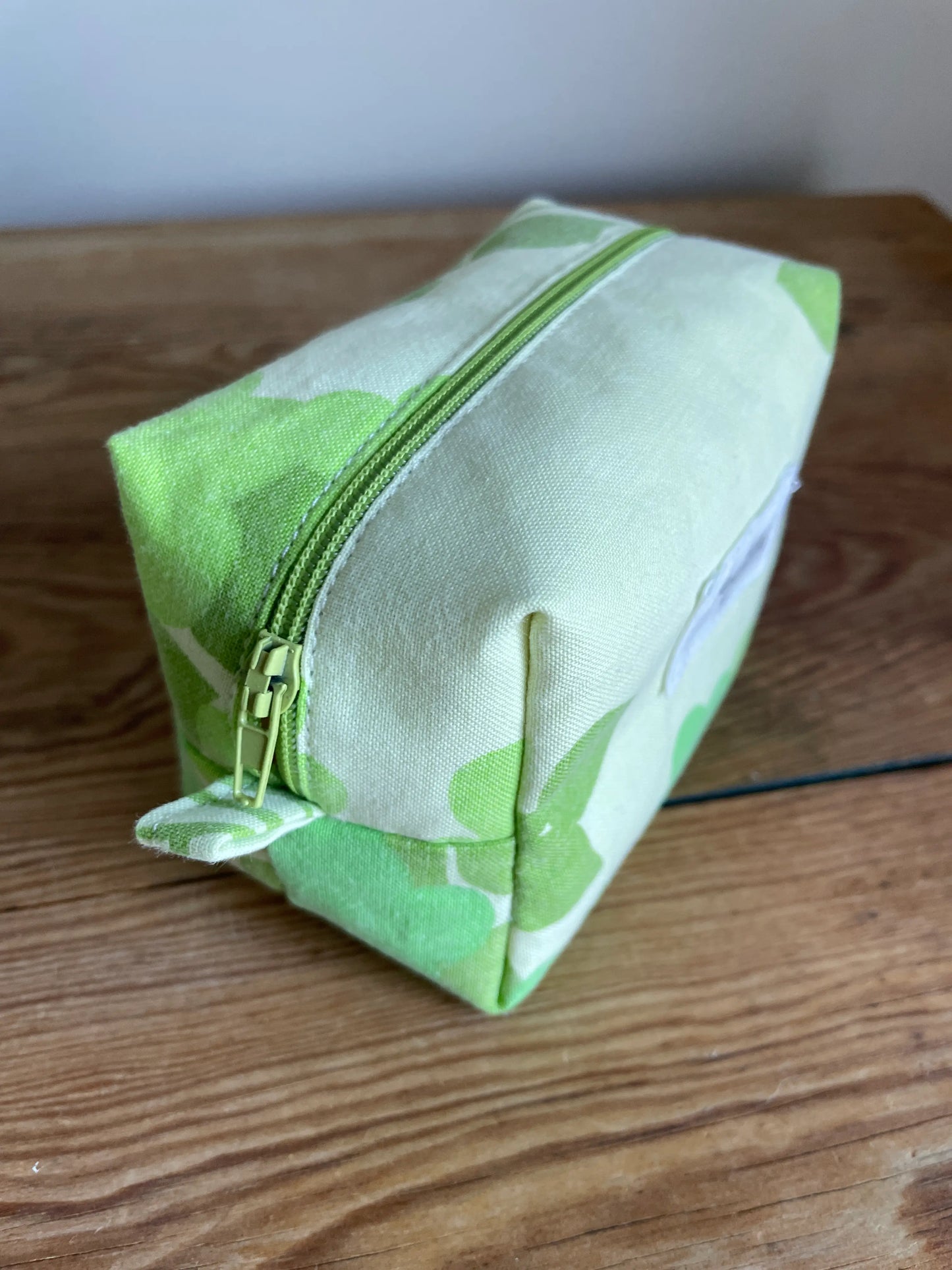 Mini boxnecessär i grönt bomullstyg med retroinspirerat blommönster i flera nyanser av grönt. Handsydd necessär med rymlig boxform som passar för sticktillbehör, virknålar, smink, toalettartiklar och annan praktisk förvaring. Det gröna mönstret ger en frisk och nostalgisk känsla inspirerad av svensk sommar och natur.