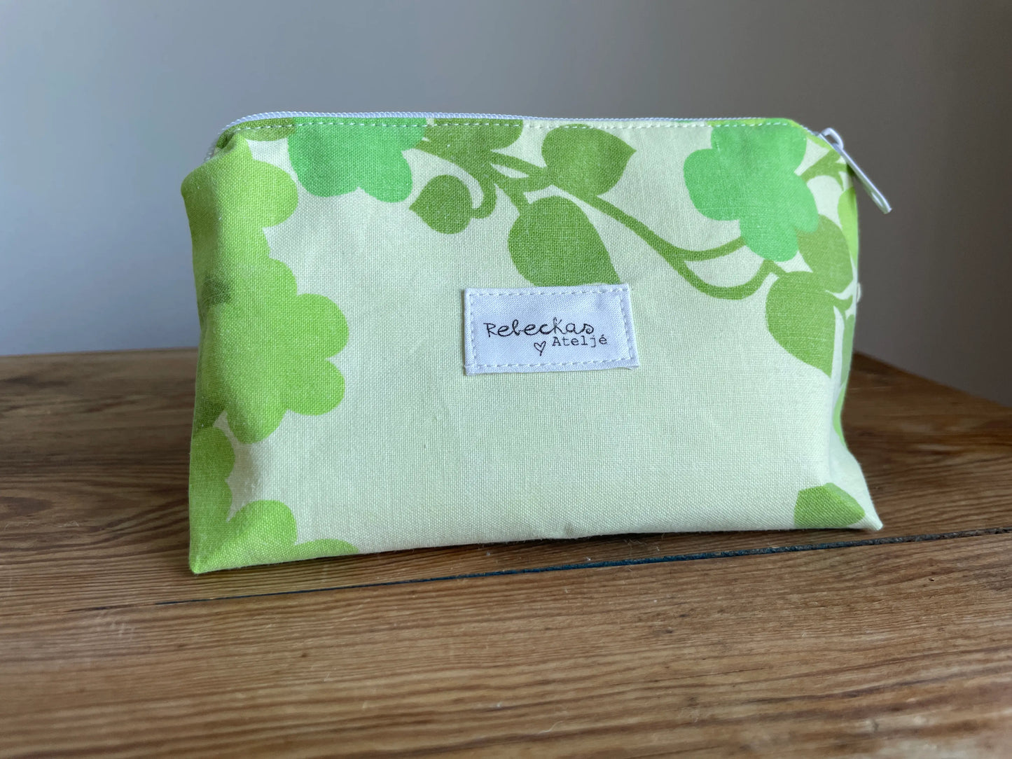 Necessär i klassisk modell i grönt bomullstyg med retroinspirerat blommönster i flera nyanser av grönt. Handsydd necessär med rymlig form som passar för sticktillbehör, virknålar, smink, toalettartiklar och annan praktisk förvaring. Det gröna mönstret ger en frisk och nostalgisk känsla inspirerad av svensk sommar och natur.