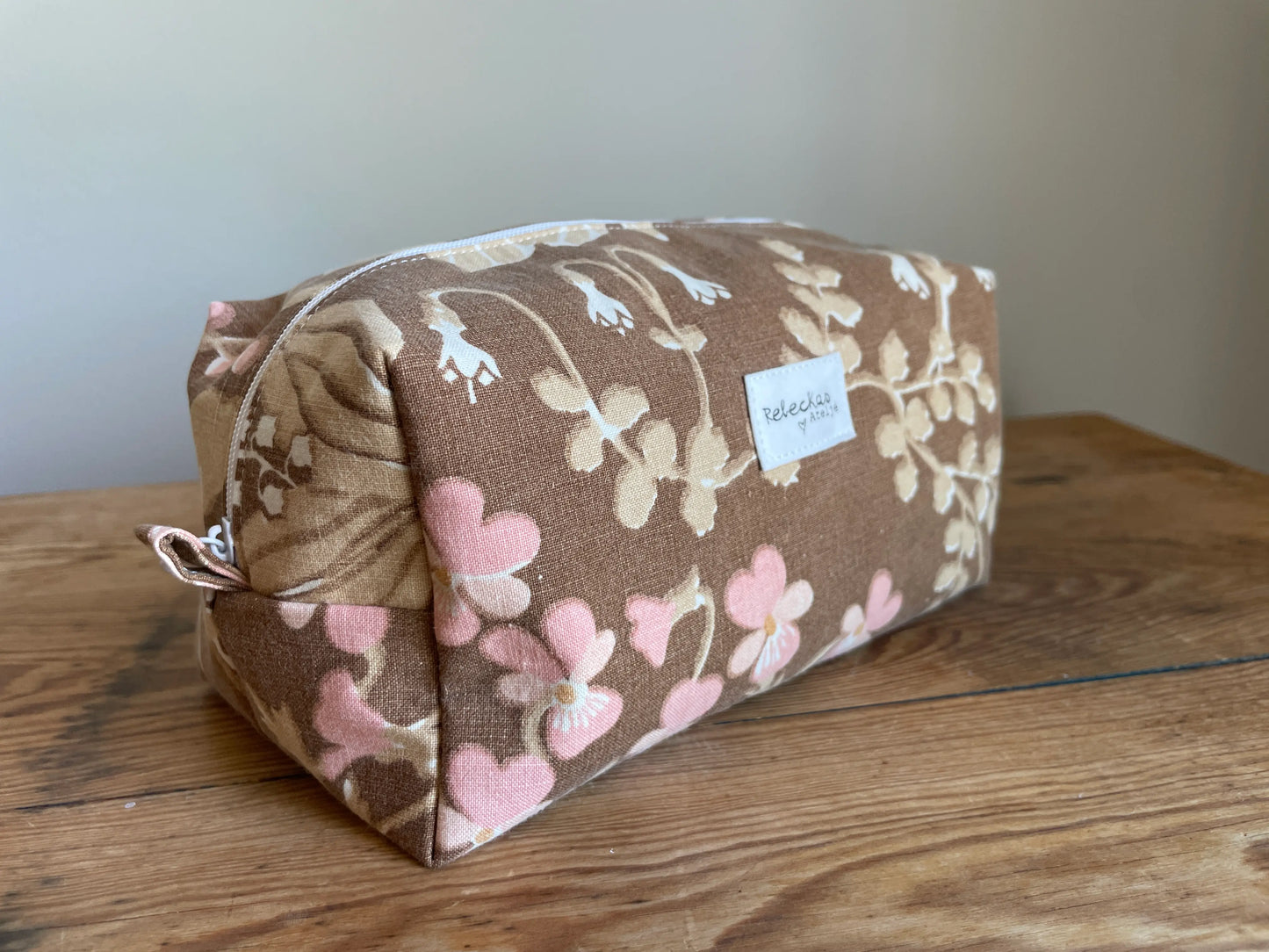 Boxnecessär i brun bomull med romantiskt blommönster i rosa, beige, creme och honungsgula toner. Handsydd necessär med rymlig boxform för smink, toalettartiklar, sticktillbehör och annan praktisk förvaring. Det vintageinspirerade blommönstret ger en varm, nostalgisk känsla med lantlig charm.