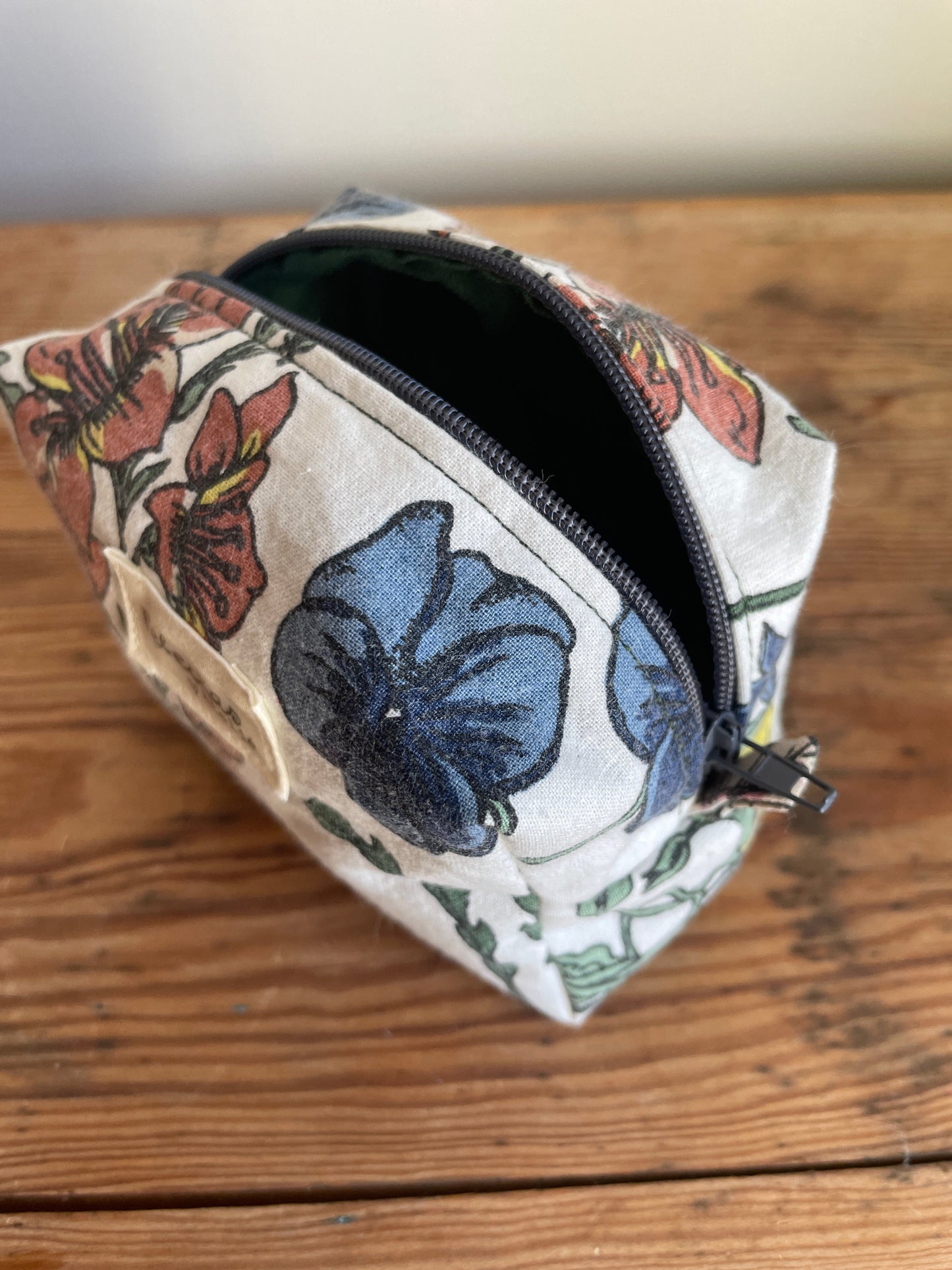 Handgjord mini boxnecessär i storblommigt tyg med vit bakgrund och flerfärgade blommor. mörkgrå dragkedja