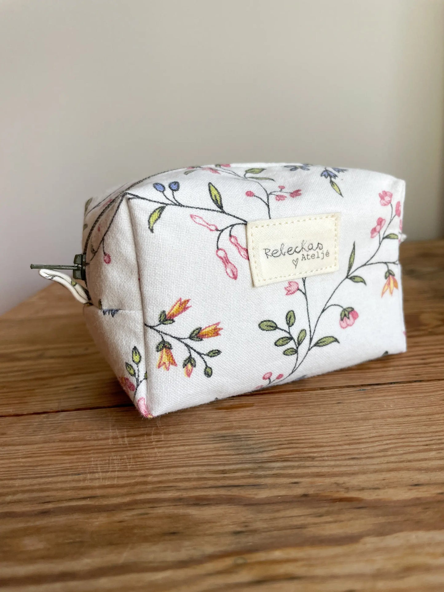 Mini Boxnecessär med blommigt tyg i vitt och grönt, flerfärgade blommor och mörkgrönt blixtlås.