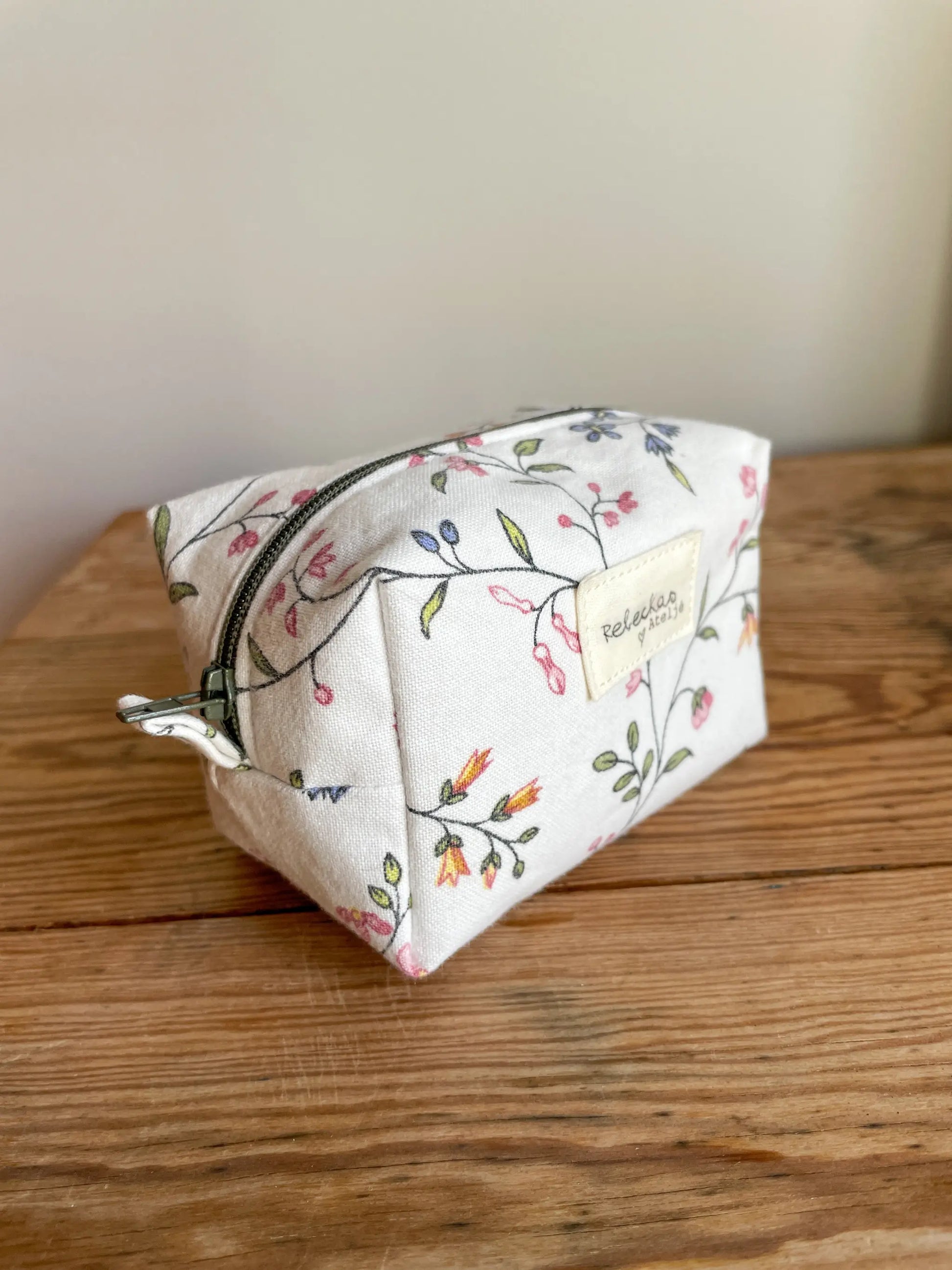 Mini Boxnecessär med blommigt tyg i vitt och grönt, flerfärgade blommor och mörkgrönt blixtlås.