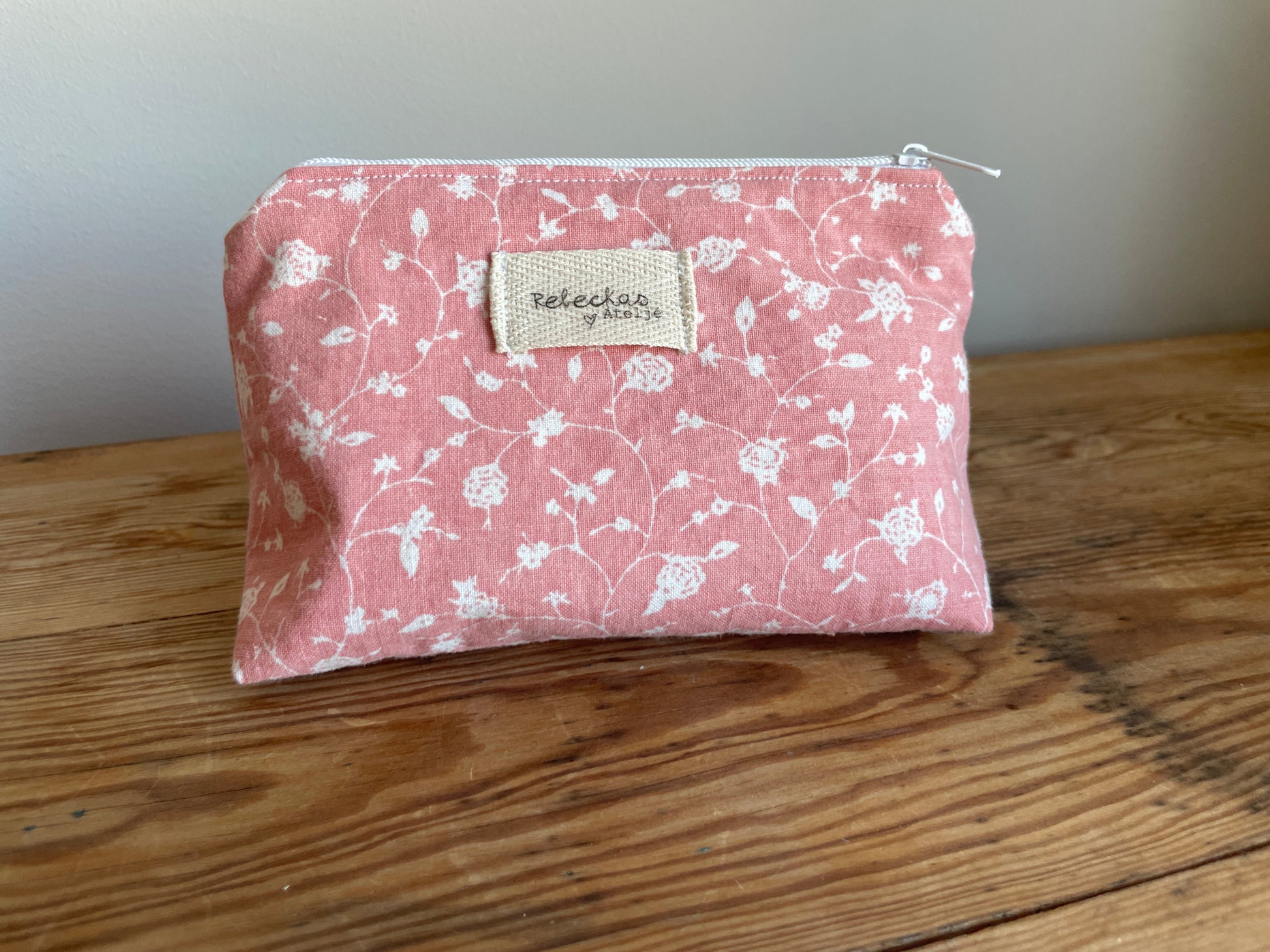 Klassisk necessär i tyg med rosa mönster och vita blommor, med dragkedja upptill