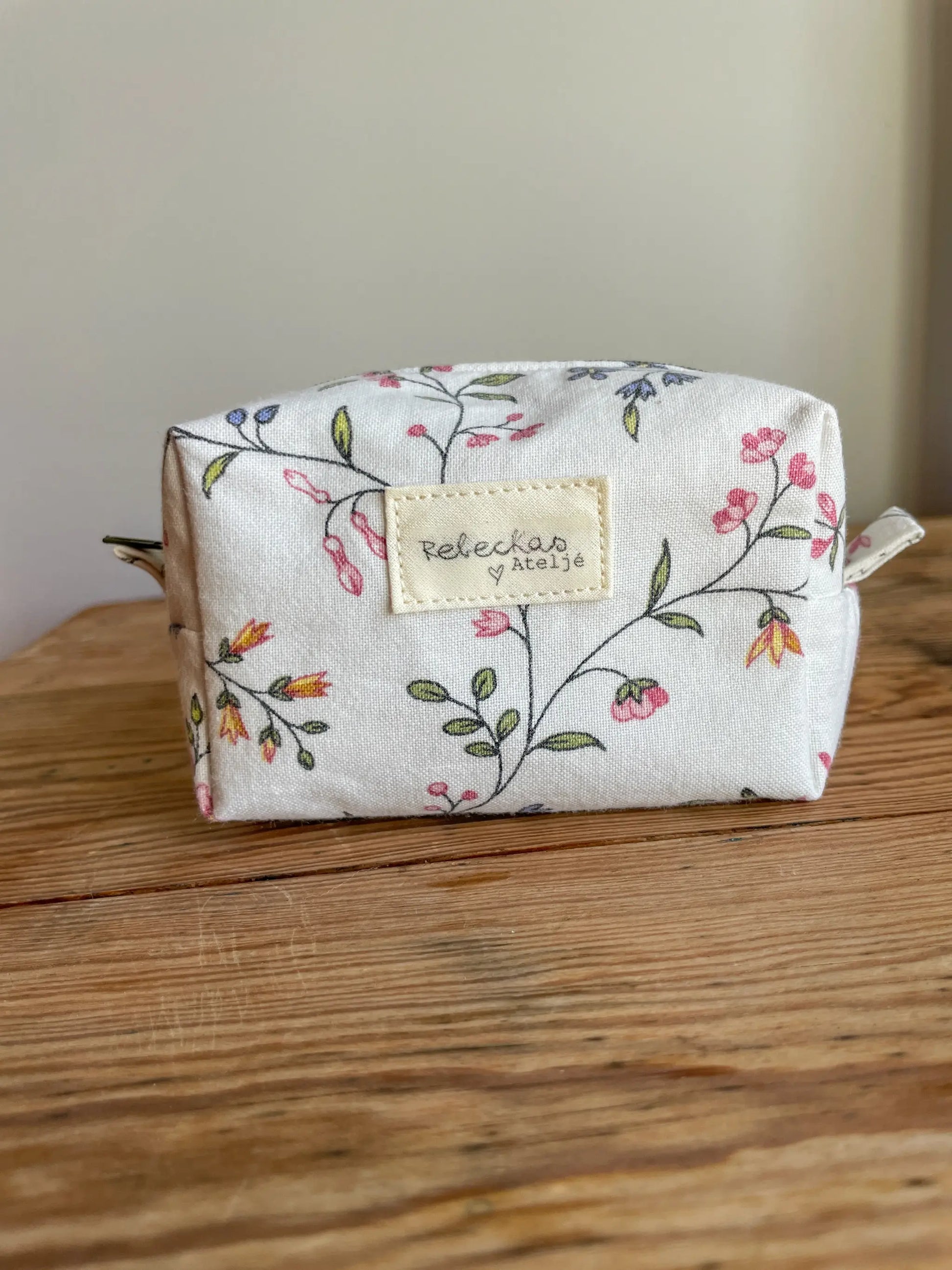 Mini Boxnecessär med blommigt tyg i vitt och grönt, flerfärgade blommor och mörkgrönt blixtlås.