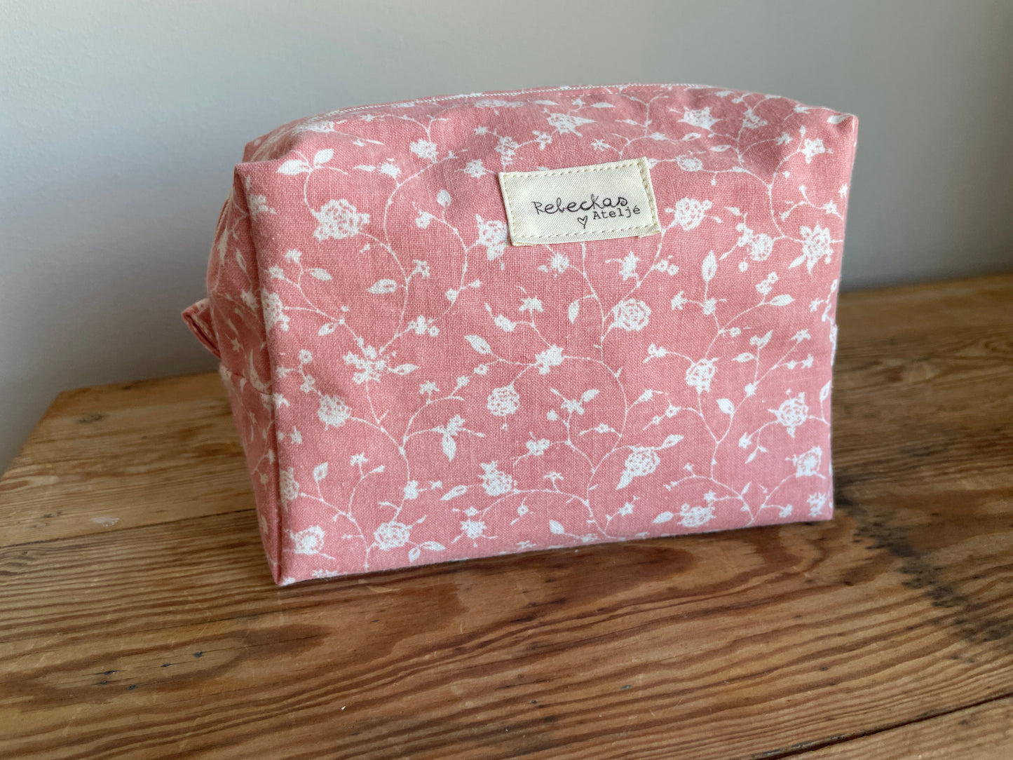 Handgjord boxnecessär i tyg med rosa bakgrund, små vita blommor och dragkedja