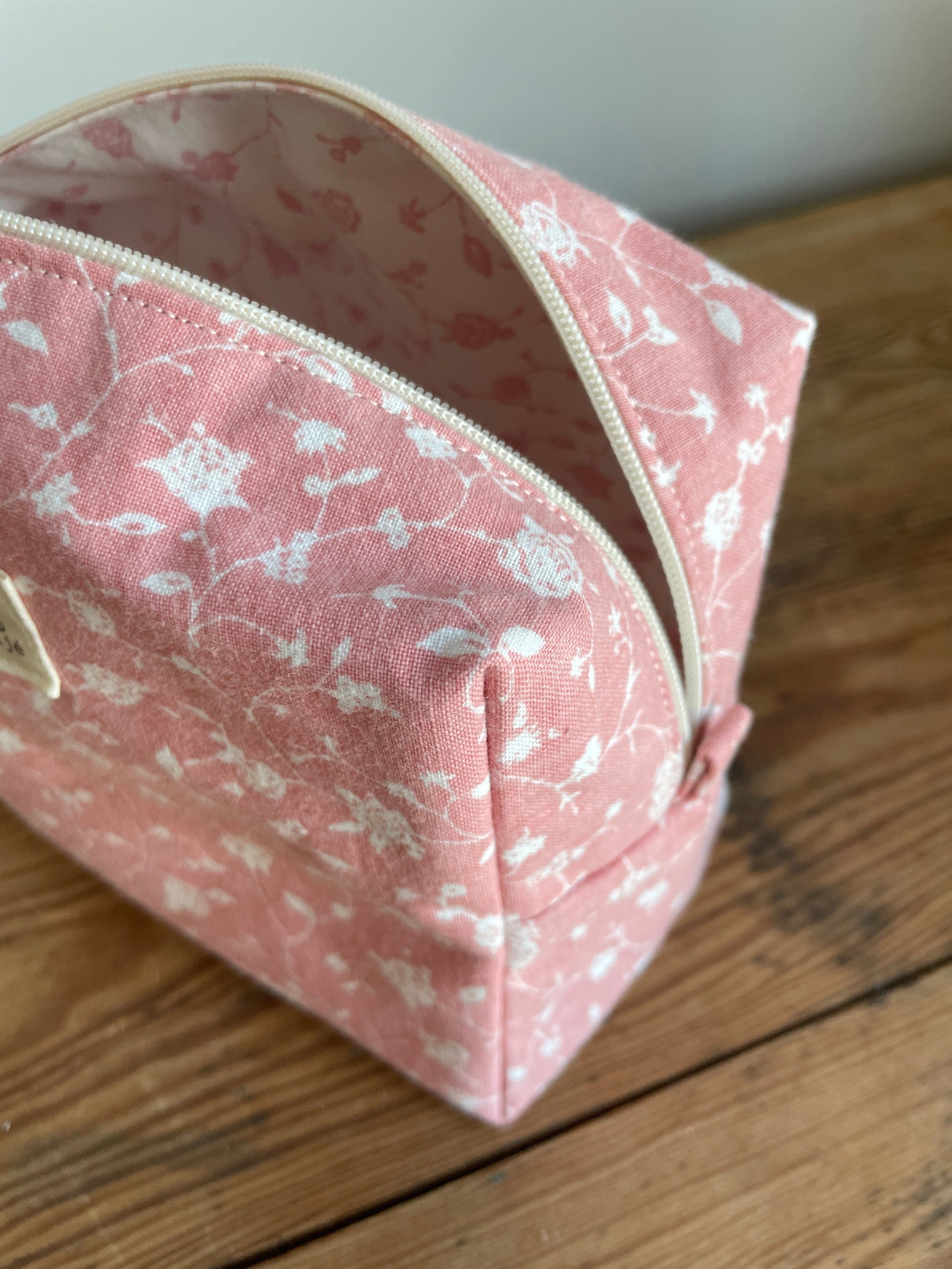 Handgjord boxnecessär i tyg med rosa bakgrund, små vita blommor och dragkedja