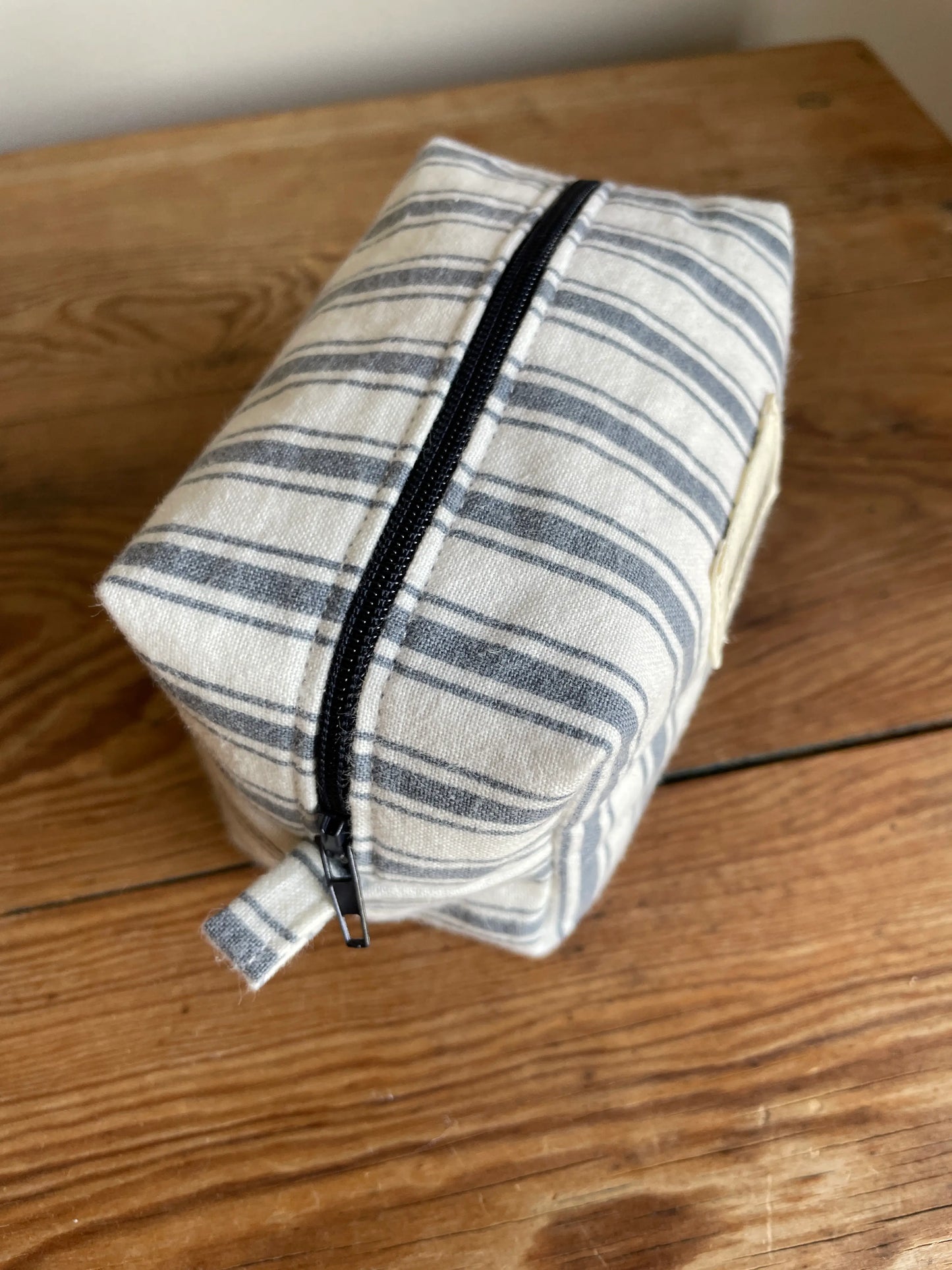 Mini Boxnecessär med vit och grå/blå randigt tyg, mörkgrått blixtlås.