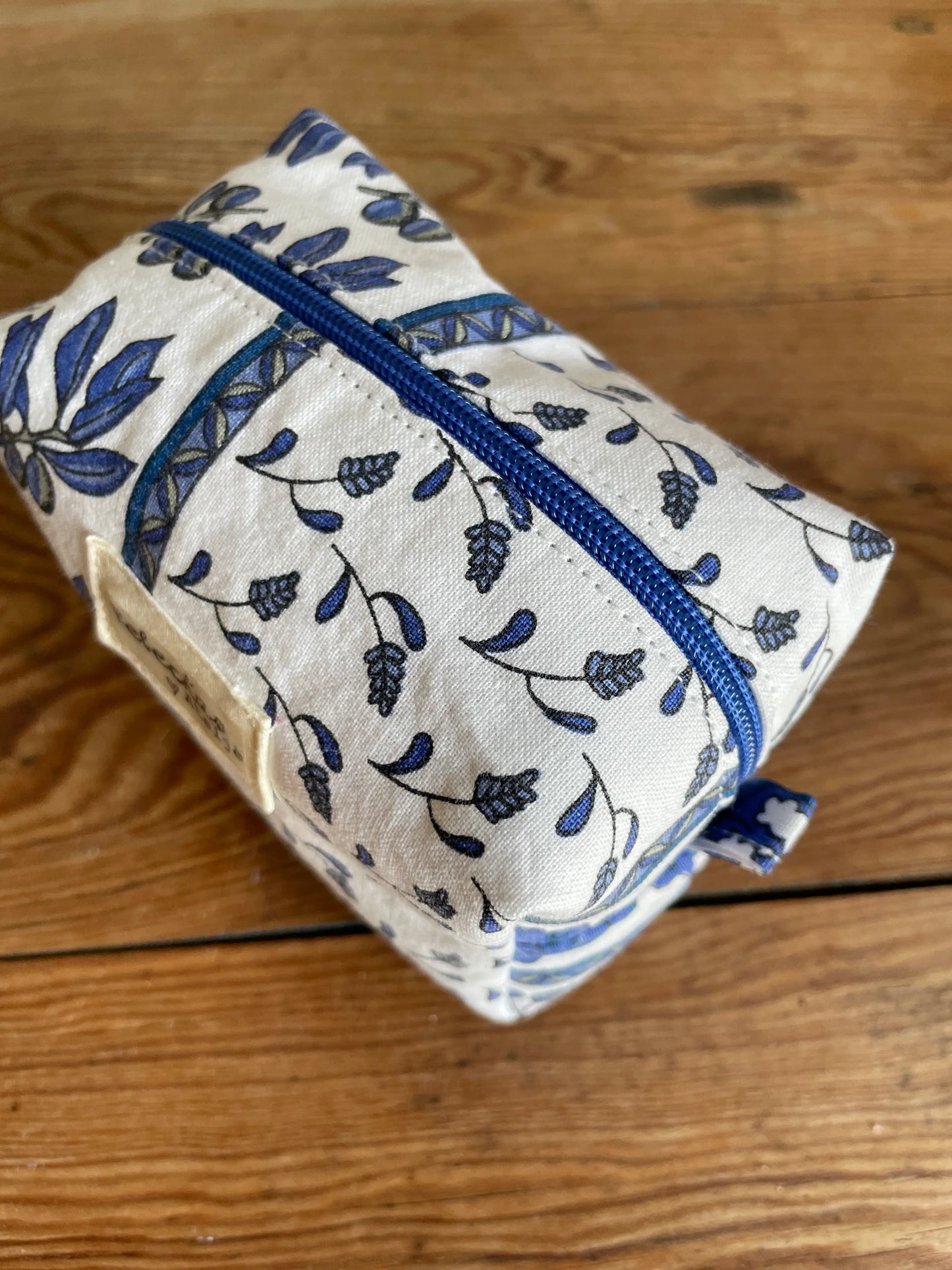 Mini boxnecessär i vitt tyg med blått blommönster och olivkvistar, handsydd med blå dragkedja.