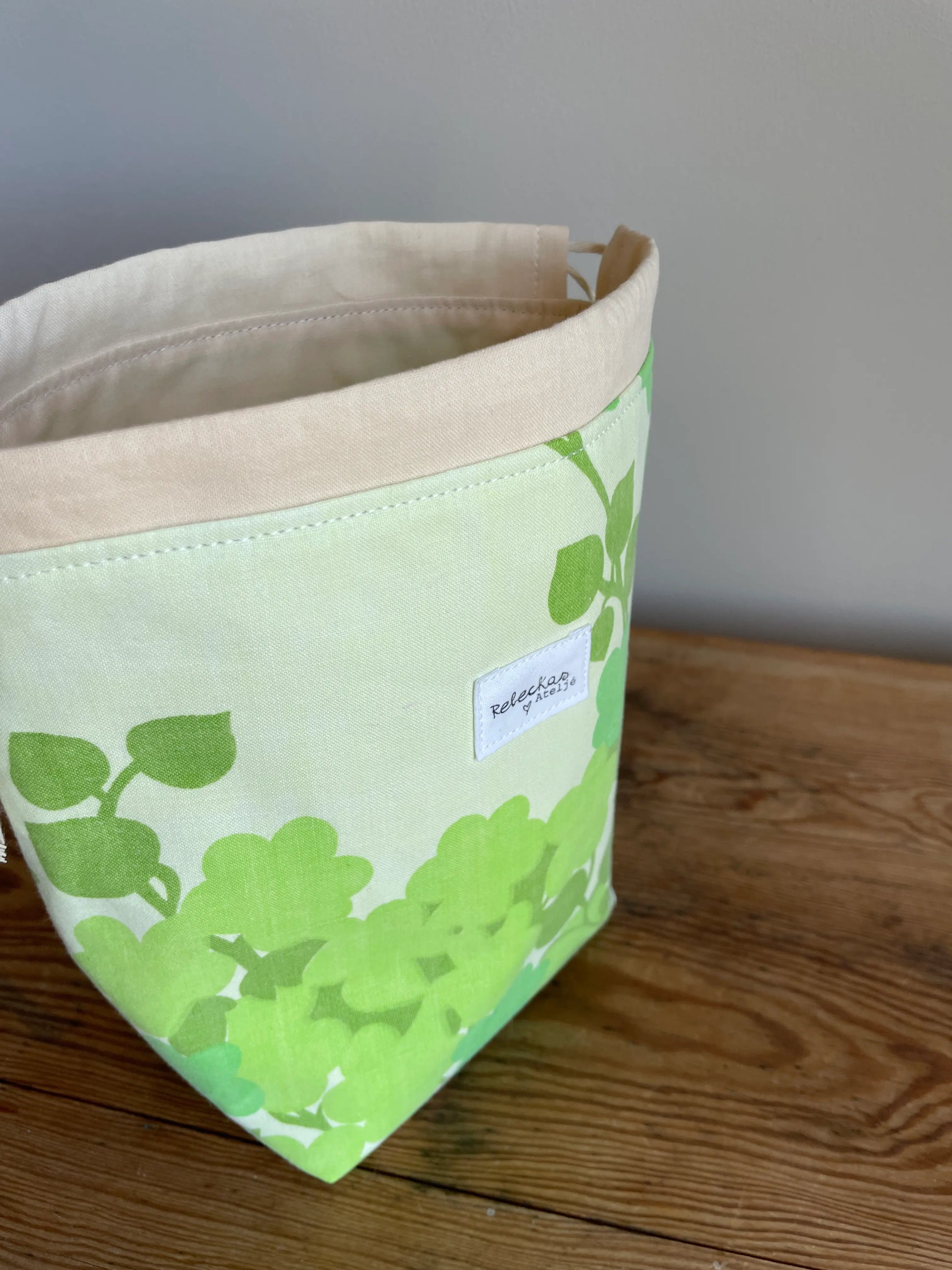 Handsydd liten projektpåse med dragsko i grönt bomullstyg med retroinspirerat blommönster. Praktisk förvaring för sockstickning, garn, virkning och andra mindre handarbetsprojekt. Rymlig projektväska i kompakt format för stickare och virkare.