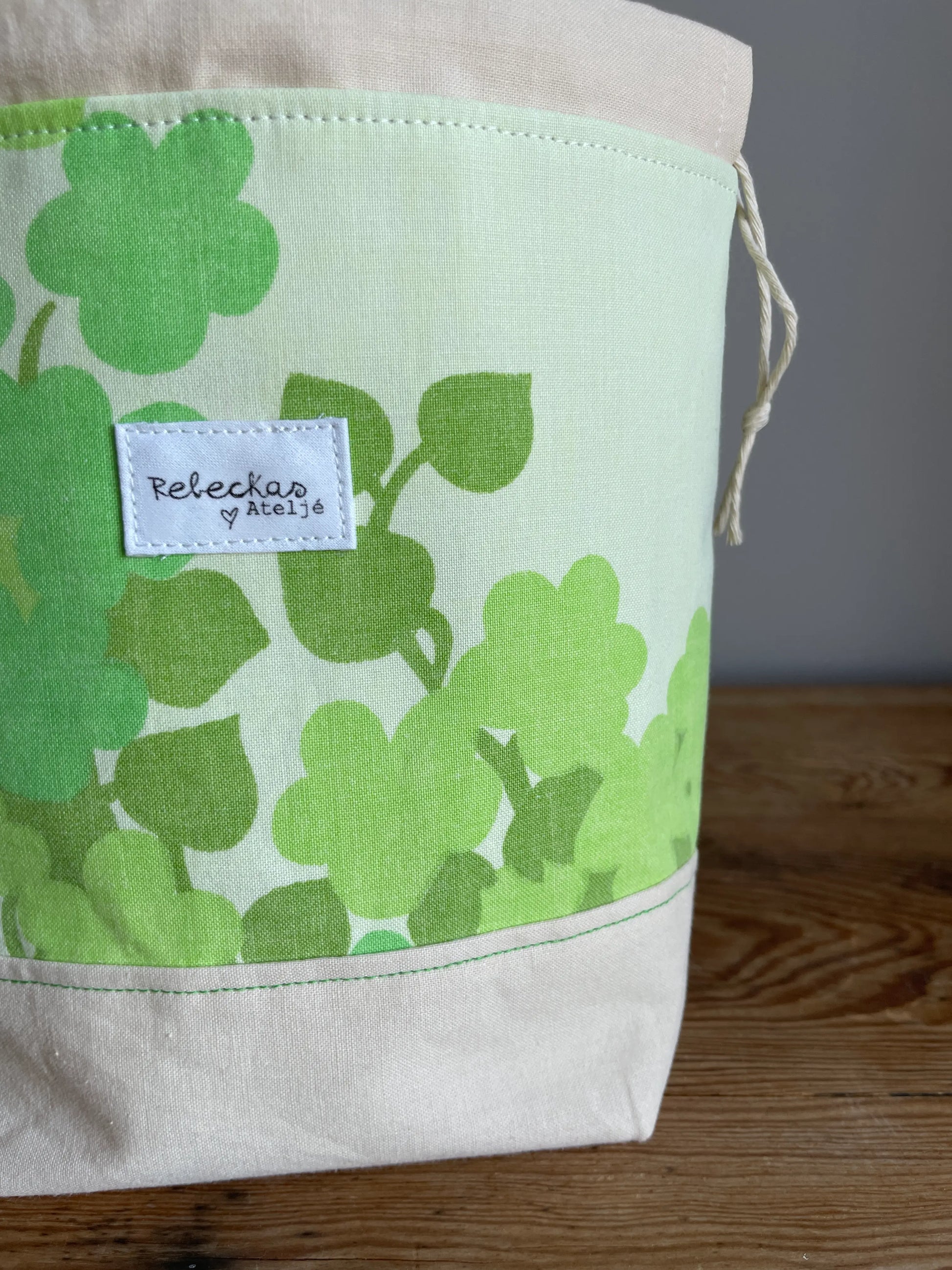 Liten projektpåse med dragsko i ljusgult bomullstyg med grönt retroinspirerat klövermönster. Handsydd projektpåse för mindre stick- och virkprojekt, garnförvaring samt tillbehör som maskmarkörer, stickor och virknålar. Den ljusgula bottenfärgen och de gröna nyanserna ger väskan en ljus, somrig och nostalgisk känsla.