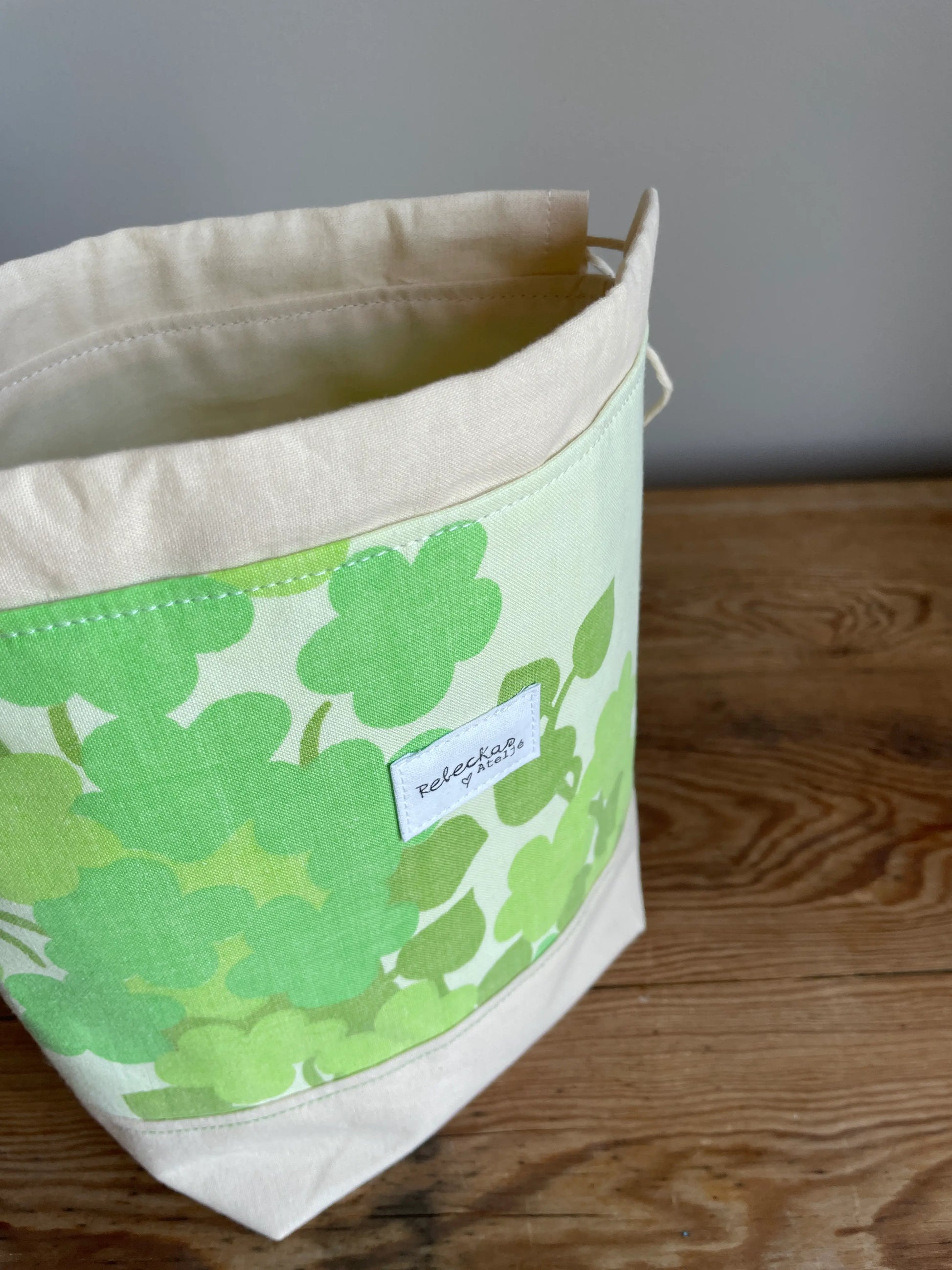 Liten projektpåse med dragsko i ljusgult bomullstyg med grönt retroinspirerat klövermönster. Handsydd projektpåse för mindre stick- och virkprojekt, garnförvaring samt tillbehör som maskmarkörer, stickor och virknålar. Den ljusgula bottenfärgen och de gröna nyanserna ger väskan en ljus, somrig och nostalgisk känsla.