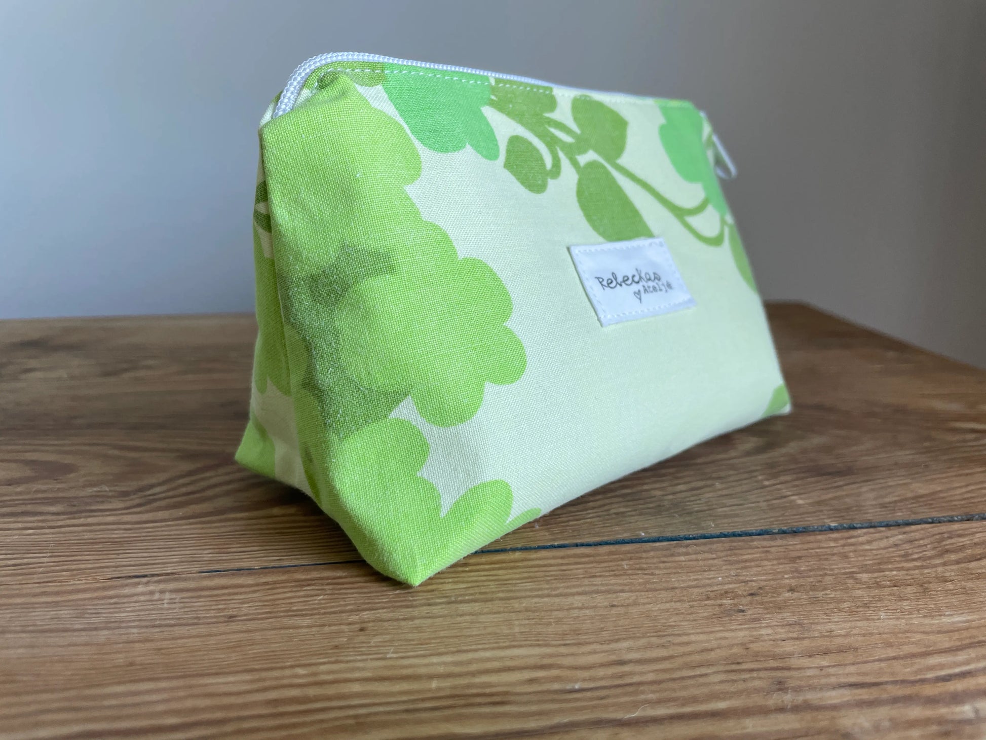 Necessär i klassisk modell i grönt bomullstyg med retroinspirerat blommönster i flera nyanser av grönt. Handsydd necessär med rymlig form som passar för sticktillbehör, virknålar, smink, toalettartiklar och annan praktisk förvaring. Det gröna mönstret ger en frisk och nostalgisk känsla inspirerad av svensk sommar och natur.