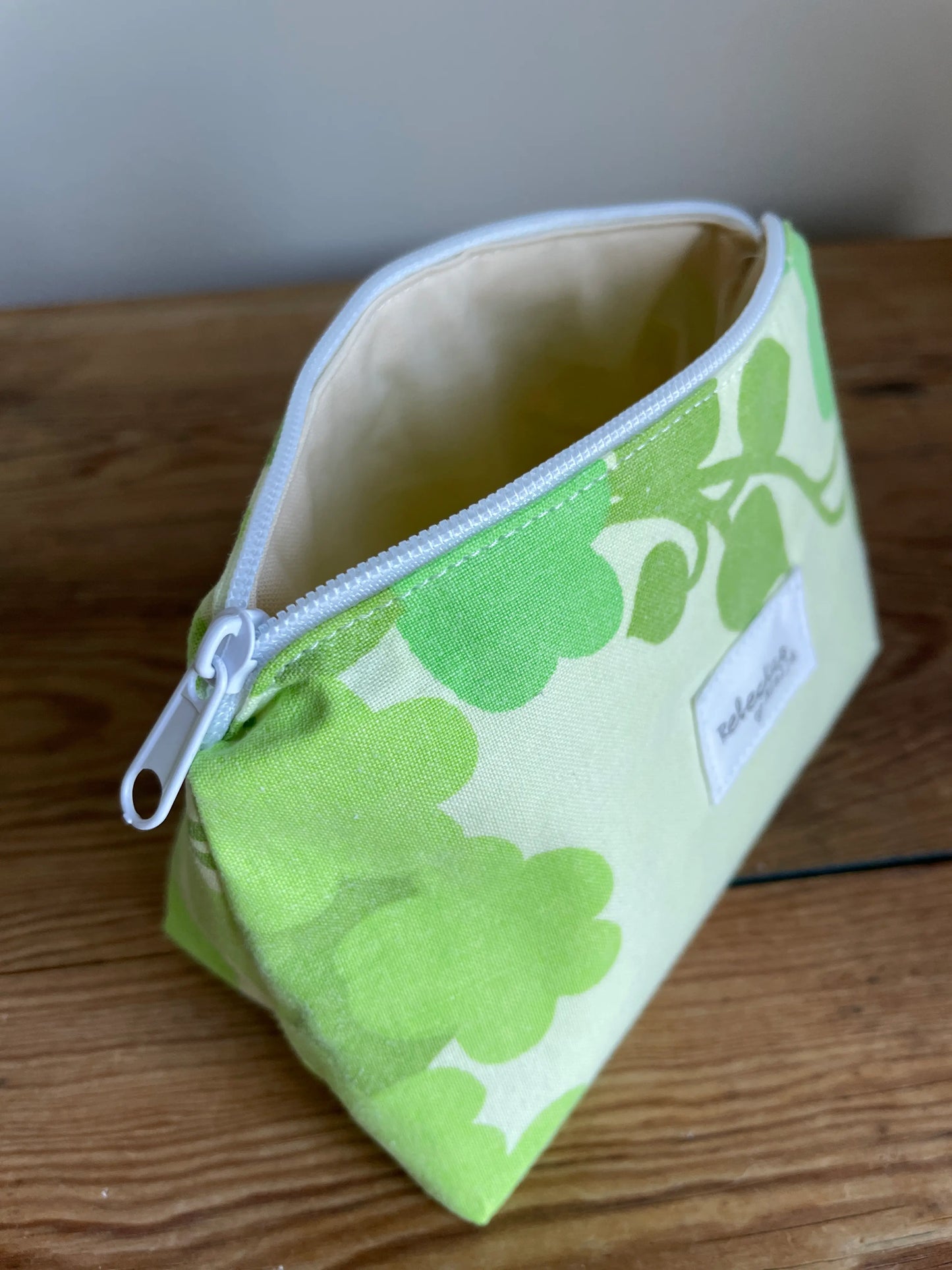 Necessär i klassisk modell i grönt bomullstyg med retroinspirerat blommönster i flera nyanser av grönt. Handsydd necessär med rymlig form som passar för sticktillbehör, virknålar, smink, toalettartiklar och annan praktisk förvaring. Det gröna mönstret ger en frisk och nostalgisk känsla inspirerad av svensk sommar och natur.