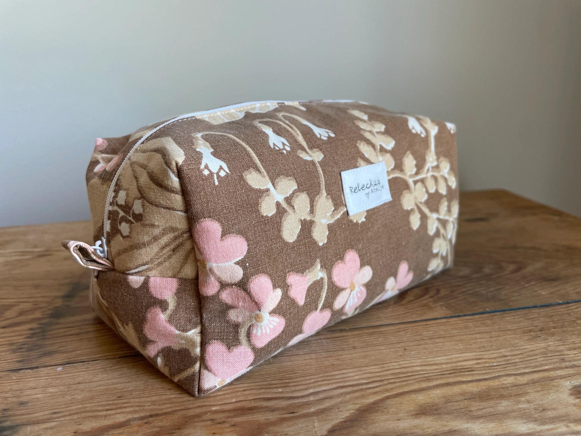 Boxnecessär i brun bomull med romantiskt blommönster i rosa, beige, creme och honungsgula toner. Handsydd necessär med rymlig boxform för smink, toalettartiklar, sticktillbehör och annan praktisk förvaring. Det vintageinspirerade blommönstret ger en varm, nostalgisk känsla med lantlig charm.