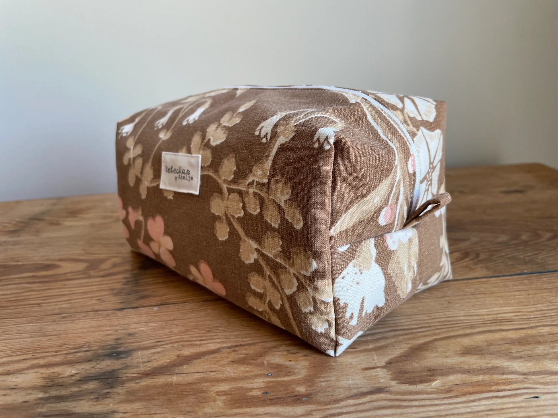 Boxnecessär i brun bomull med romantiskt blommönster i rosa, beige, creme och honungsgula toner. Handsydd necessär med rymlig boxform för smink, toalettartiklar, sticktillbehör och annan praktisk förvaring. Det vintageinspirerade blommönstret ger en varm, nostalgisk känsla med lantlig charm.