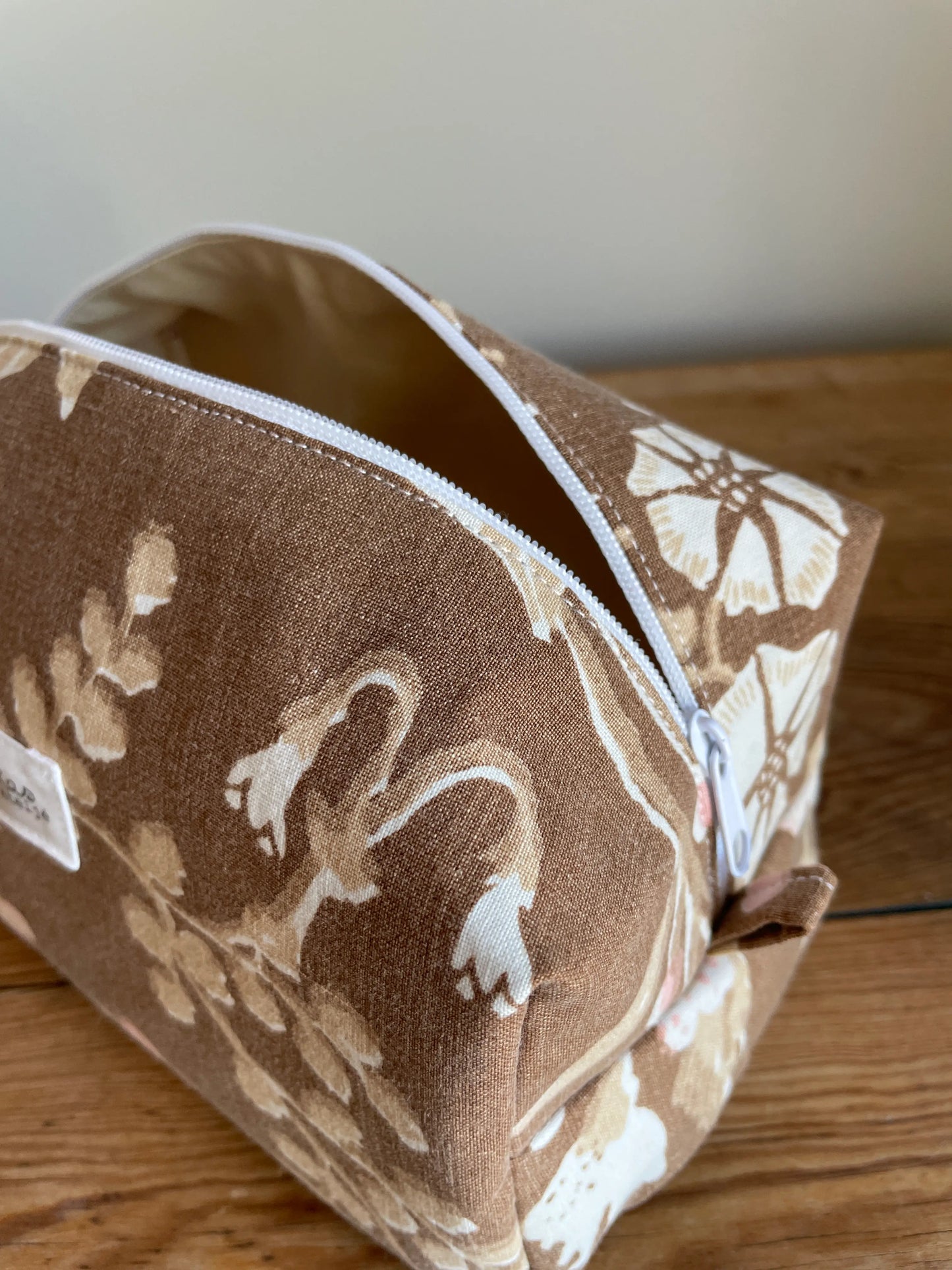Boxnecessär i brun bomull med romantiskt blommönster i rosa, beige, creme och honungsgula toner. Handsydd necessär med rymlig boxform för smink, toalettartiklar, sticktillbehör och annan praktisk förvaring. Det vintageinspirerade blommönstret ger en varm, nostalgisk känsla med lantlig charm.
